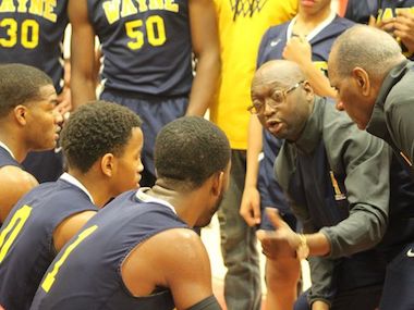 Black coach huddles with players